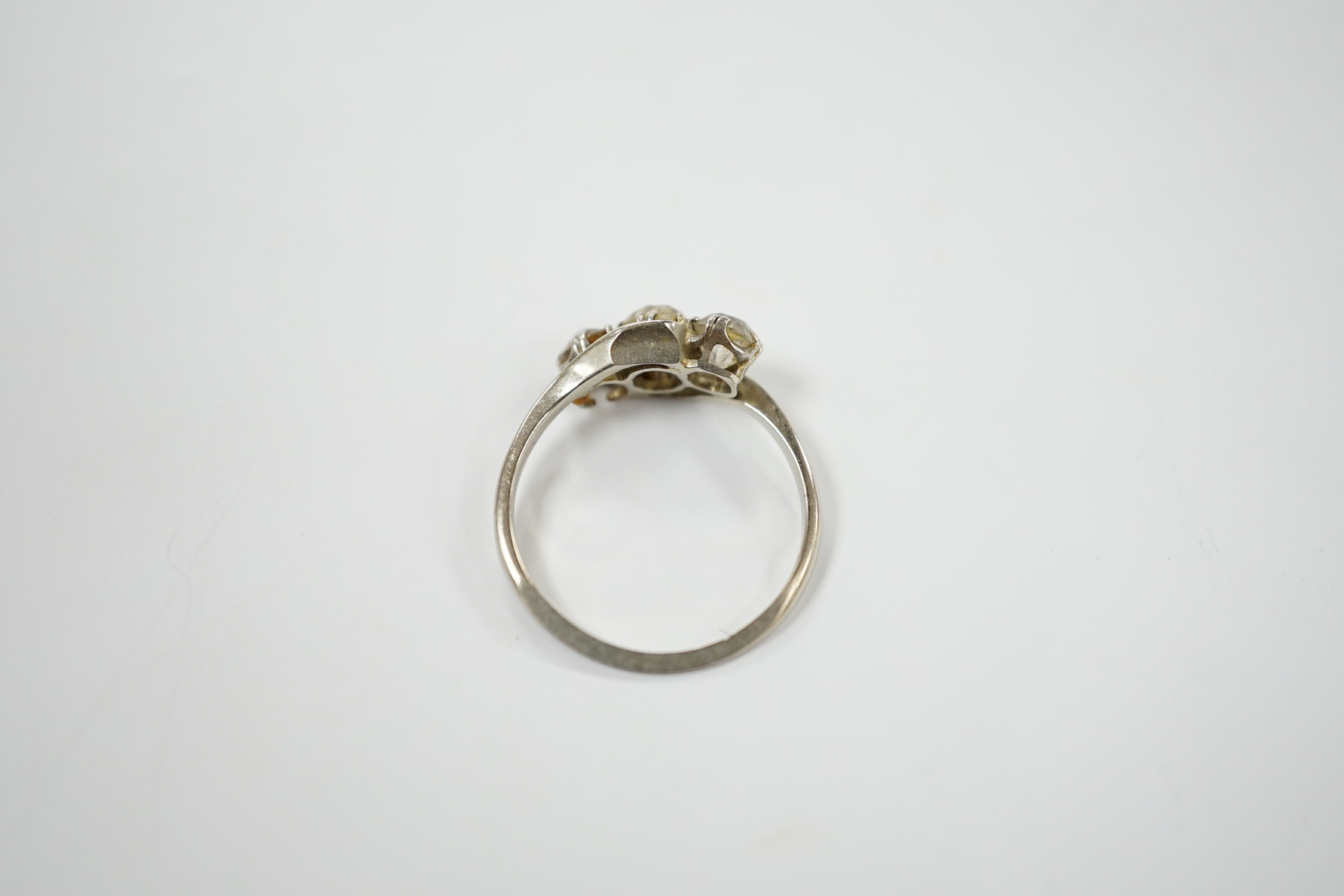 An 18ct, plat and three stone old mine cut diamond set crossover ring, size N, gross weight 2.3 grams.